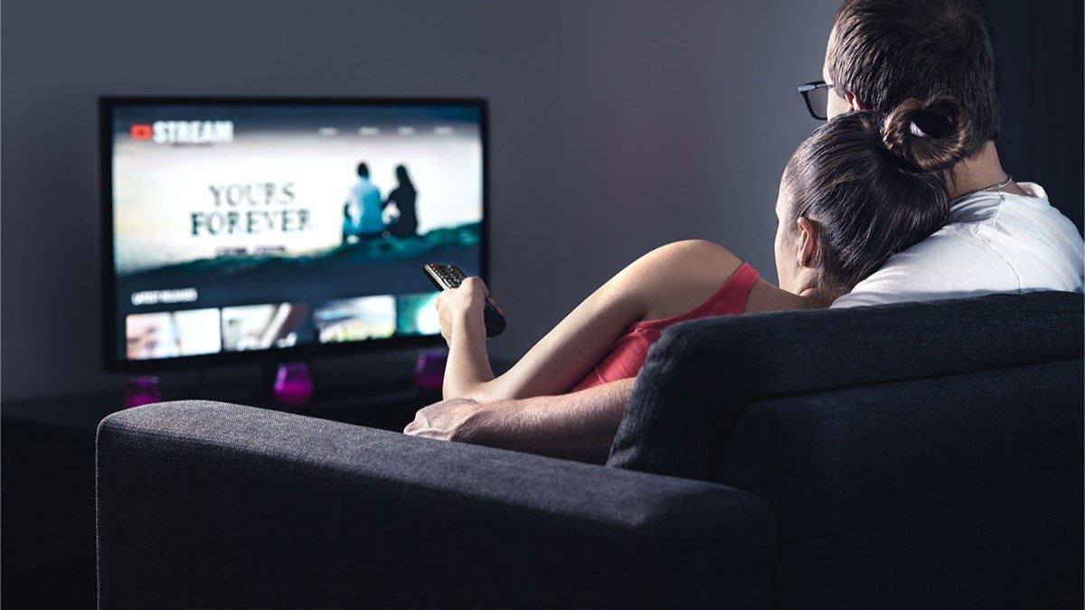 A couple watching a TV with closed captions turned on A couple watching a TV with closed captions turned on